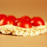 A delectable rice cake topped with fresh cherry tomatoes, perfect for healthy snack ideas.